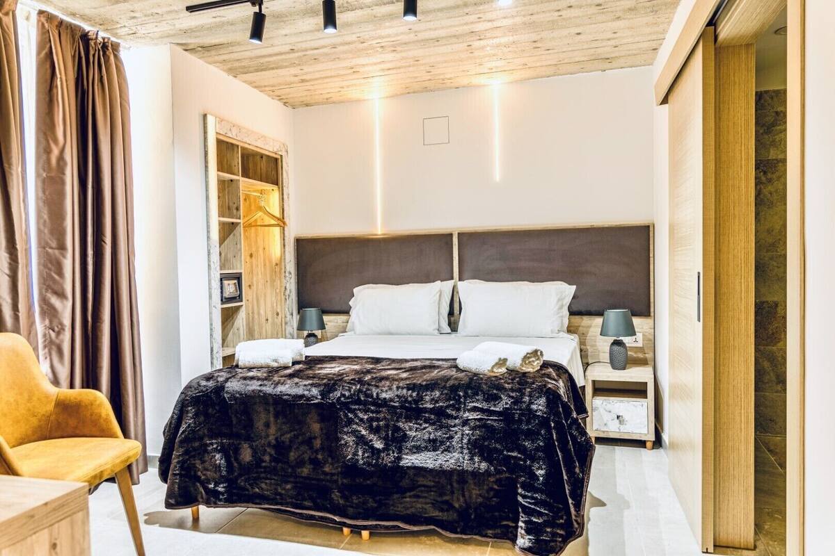 Une chambre moderne avec un grand lit, une tête de lit en bois, des tables de chevet et une armoire.
