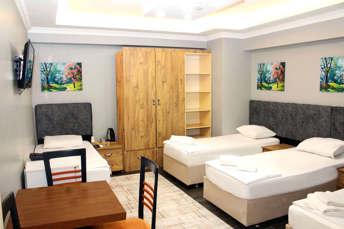 A hotel room with two beds, a wooden wardrobe, a desk, and a chair.