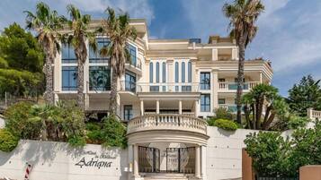 Ein mehrstöckiges Hotel mit klassischer Fassade, Palmen und einem verschlossenen Eingang.
