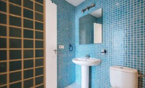Ein Badezimmer mit blauen Fliesen, einem weißen Waschbecken und einer Toilette.