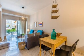 Een moderne woonkamer met een bank, een houten eettafel en een hanglamp.