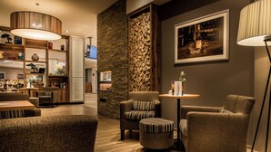 A modern interior with a seating area, a wooden wall, and a framed picture on the wall. - Akzent Hotel Köhler (Giessen)