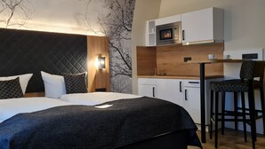 A modern hotel room with a large bed, a desk with a chair, a microwave, and a small kitchenette. - Akzent Hotel Köhler (Giessen)
