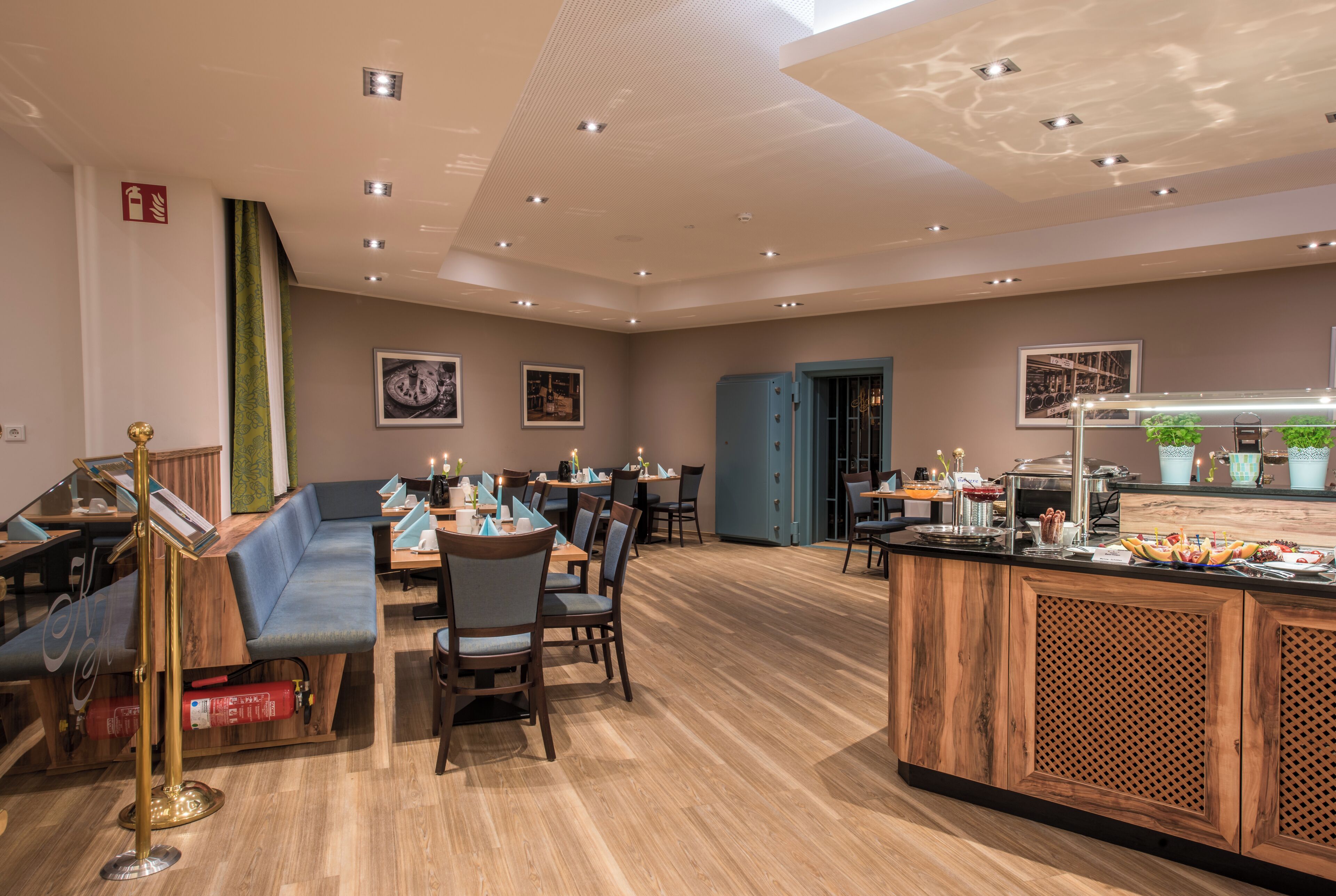 A restaurant with wooden flooring, tables with chairs, a bar area, and framed pictures on the walls.