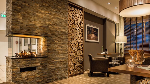 A modern interior with a stone fireplace, comfortable seating, and a dining area. - Akzent Hotel Köhler (Giessen)