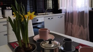 Una cocina moderna con armarios blancos, un lavamanos de acero inoxidable y un ventanal con cortinas translúcidas.