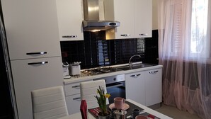 Una cocina moderna con armarios blancos, una campana extractora de acero inoxidable y un backsplash de azulejos negros.