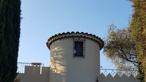 Ein Gebäude mit einem runden Turm, einer Garage und einem eingezäunten Bereich.