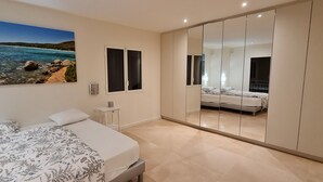 Ein Schlafzimmer mit einem Bett, einem Nachttisch, einem Spiegel und einem Gemälde einer Küstenlandschaft.