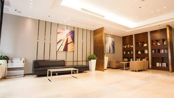A modern lobby with a sofa, coffee table, bookshelves, and a potted plant.