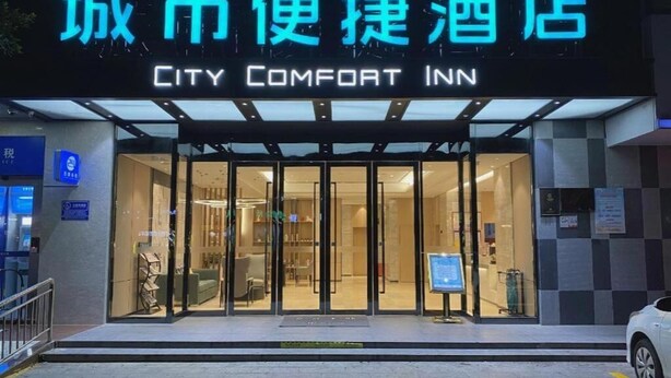 The exterior of City Comfort Inn with a glass entrance and a sign above. - City Comfort Inn (Zhanjiang)