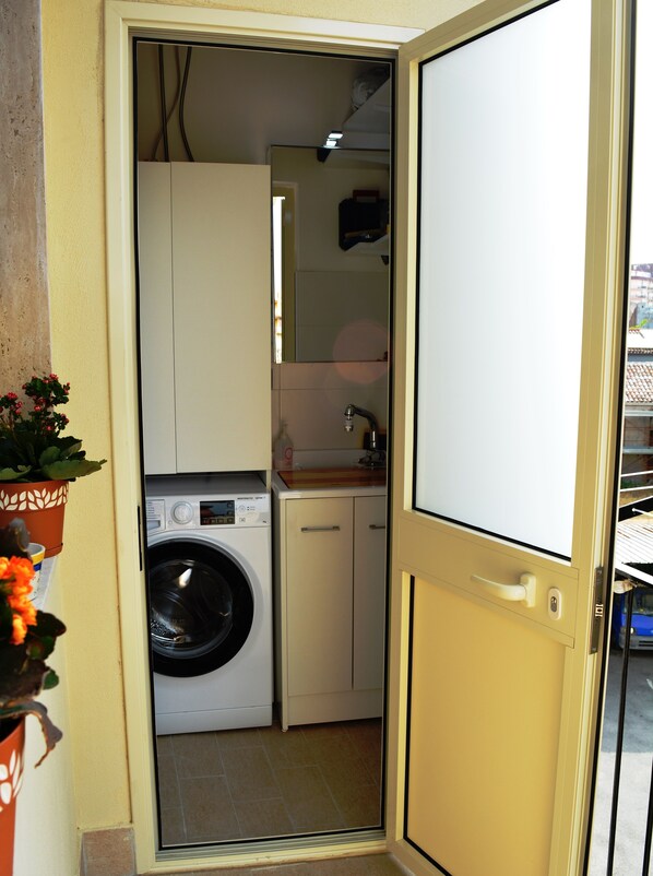 A compact laundry room with a washing machine, a sink, and cabinets.