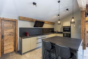 Cozinha moderna com ilha central, eletrodomésticos embutidos e iluminação pendente.