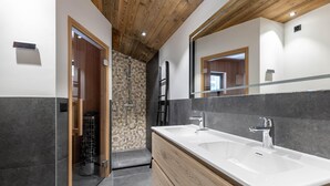 Une salle de bain moderne avec deux lavabos, une douche et un plafond en bois.