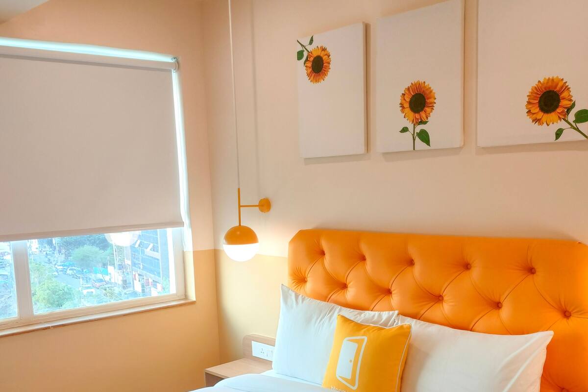 A bedroom with a large bed, a window, and wall-mounted artwork.