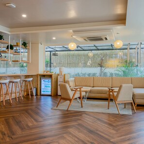A modern interior with a wooden floor, a sofa, a small table, and a refrigerator. - Bloom Hotel - HITEC City (Hyderabad)