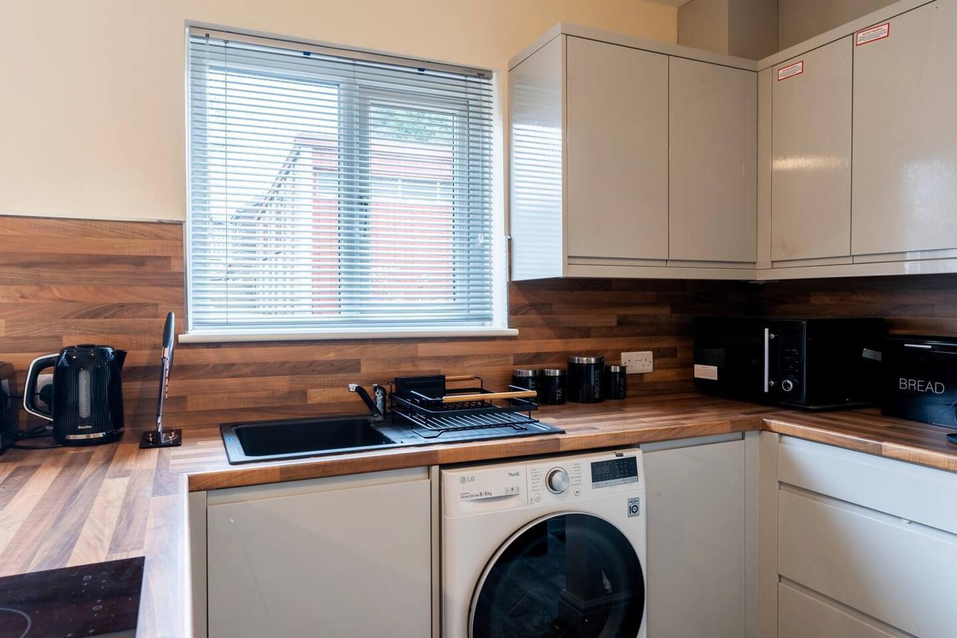 A compact kitchen with a washing machine, a coffee maker, and a microwave.