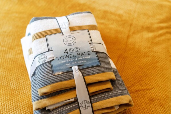 A 4-piece towel bundle with a label indicating it contains 2 bath towels and is made of 100% luxury cotton.