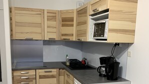 A compact kitchen with wooden cabinets, a built-in microwave, and a coffee maker.