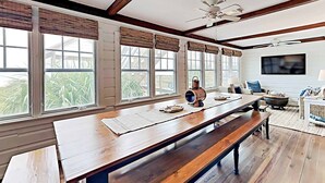 A spacious room with a long wooden table, benches, and a ceiling fan. - Ocean & Creekfront: Selah mid Island, Porches, Decks, Dock (Pawleys Island)