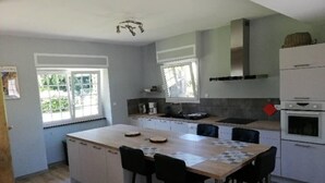 A modern kitchen with a central island, white cabinetry, and a large window providing natural light.