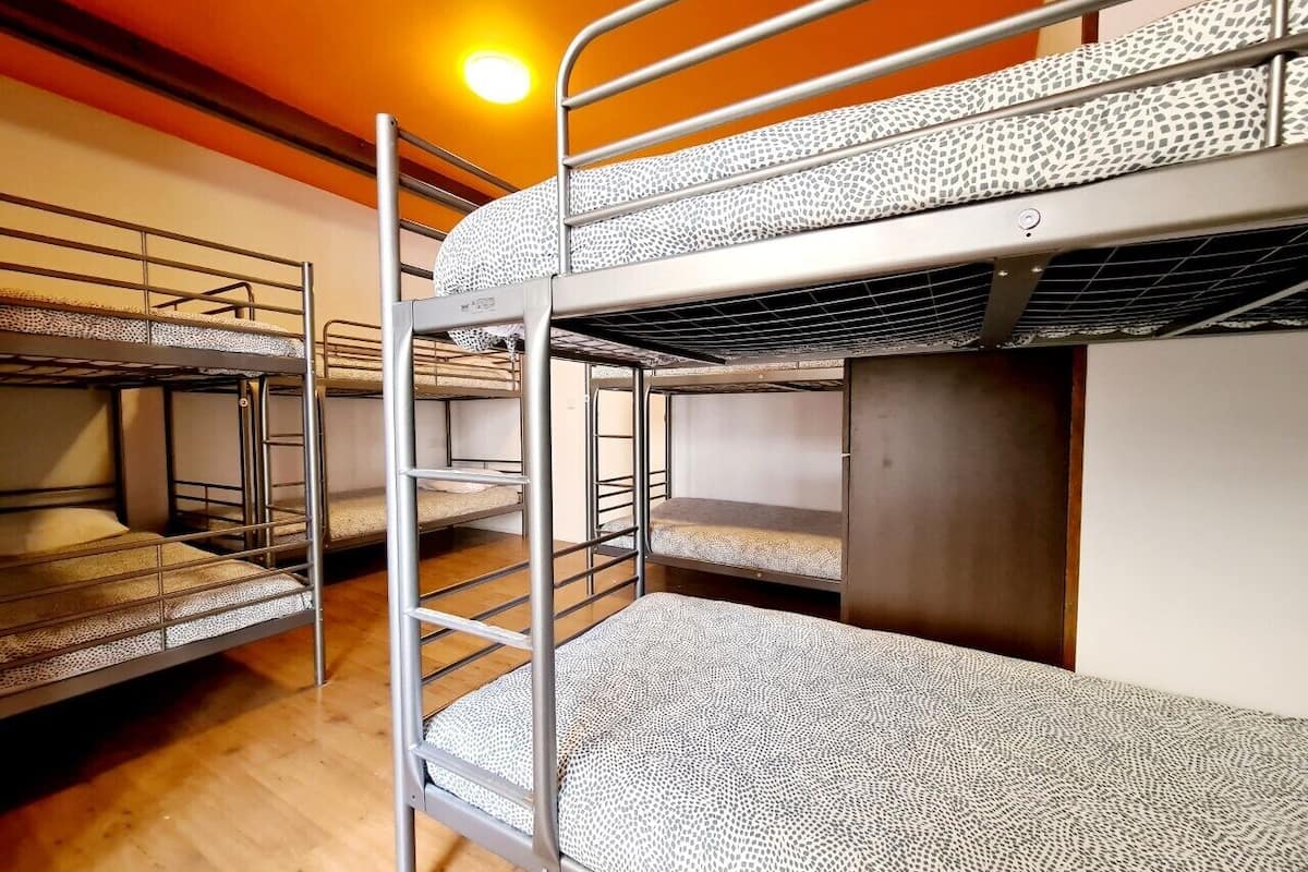 Quarto tipo dormitório com beliches, soalho de madeira e uma escada visível.