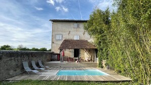 Ein Haus mit Schwimmbad, einer Holzterrasse und einem Garten.
