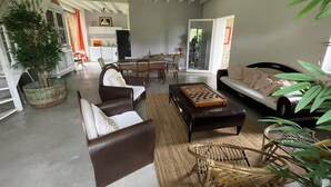 Ein geräumiges Wohnzimmer mit einer Couch, Sesseln, einem Couchtisch und einem Essbereich mit Tisch und Stühlen.