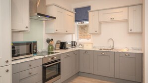 Une cuisine moderne avec des meubles gris, un four encastré, un four à micro-ondes et un évier.