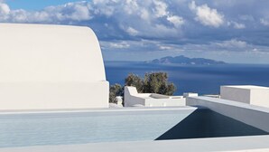 Un edificio moderno y blanco con piscina y vistas al mar y a las montañas.