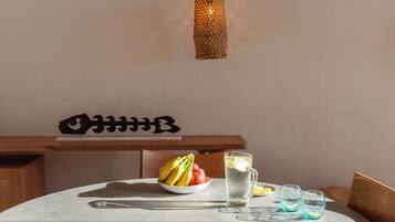 Una mesa de comedor con un cuenco de fruta, una jarra de agua y dos vasos.