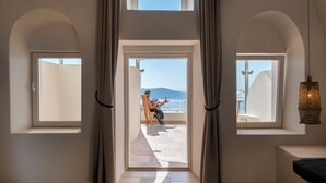 Una habitación con vistas al mar, un balcón y un amplio ventanal con cortinas.