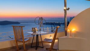 Una terraza con mesa y sillas que da a un paisaje pintoresco al atardecer.