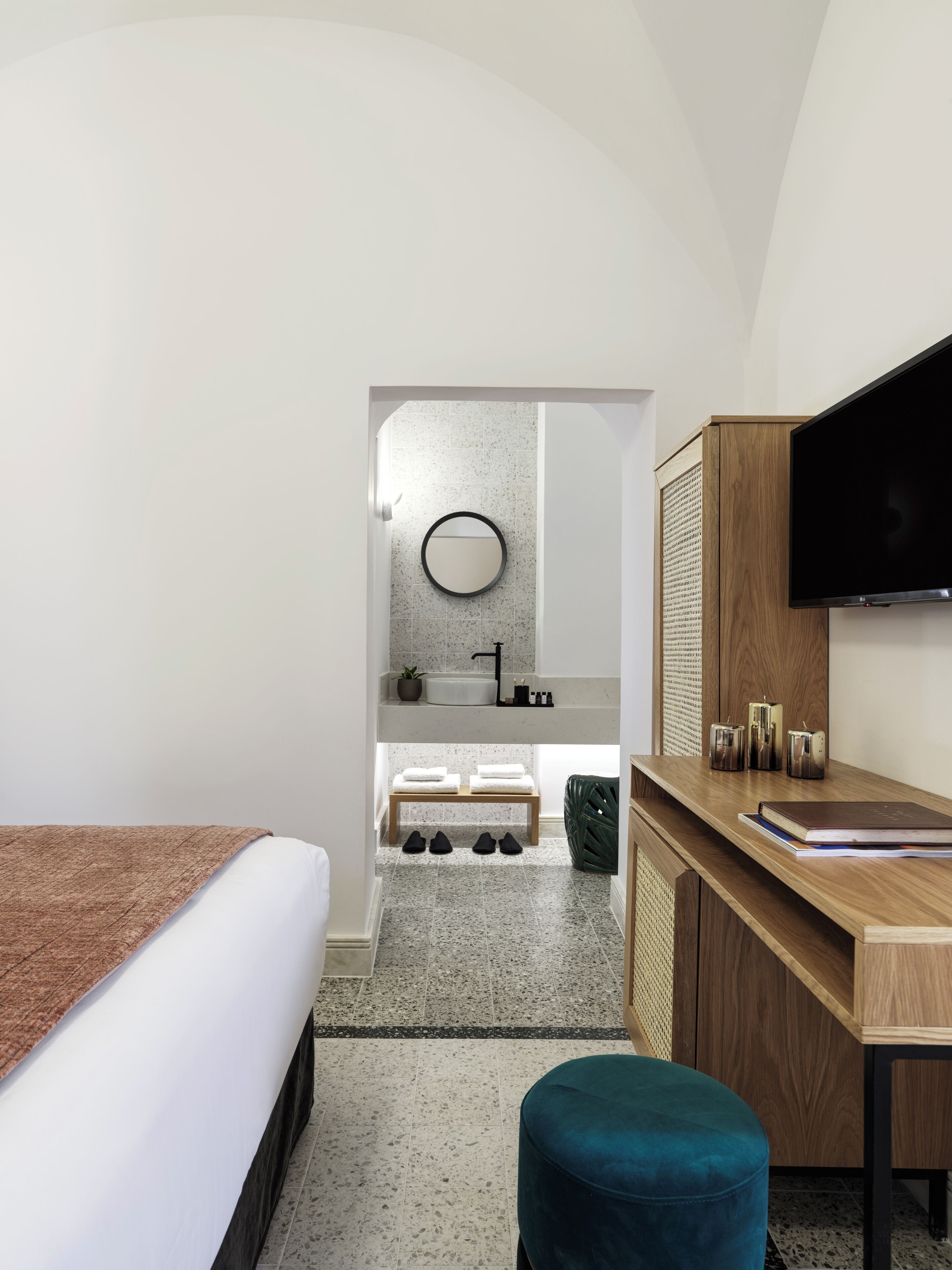 Une chambre d’hôtel moderne équipée d’un lit, d’un bureau, d’une télévision, d’un lavabo et d’un miroir.