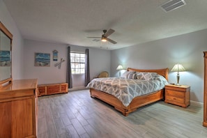 A bedroom with a wooden bed, nightstands, a ceiling fan, and a window with curtains.