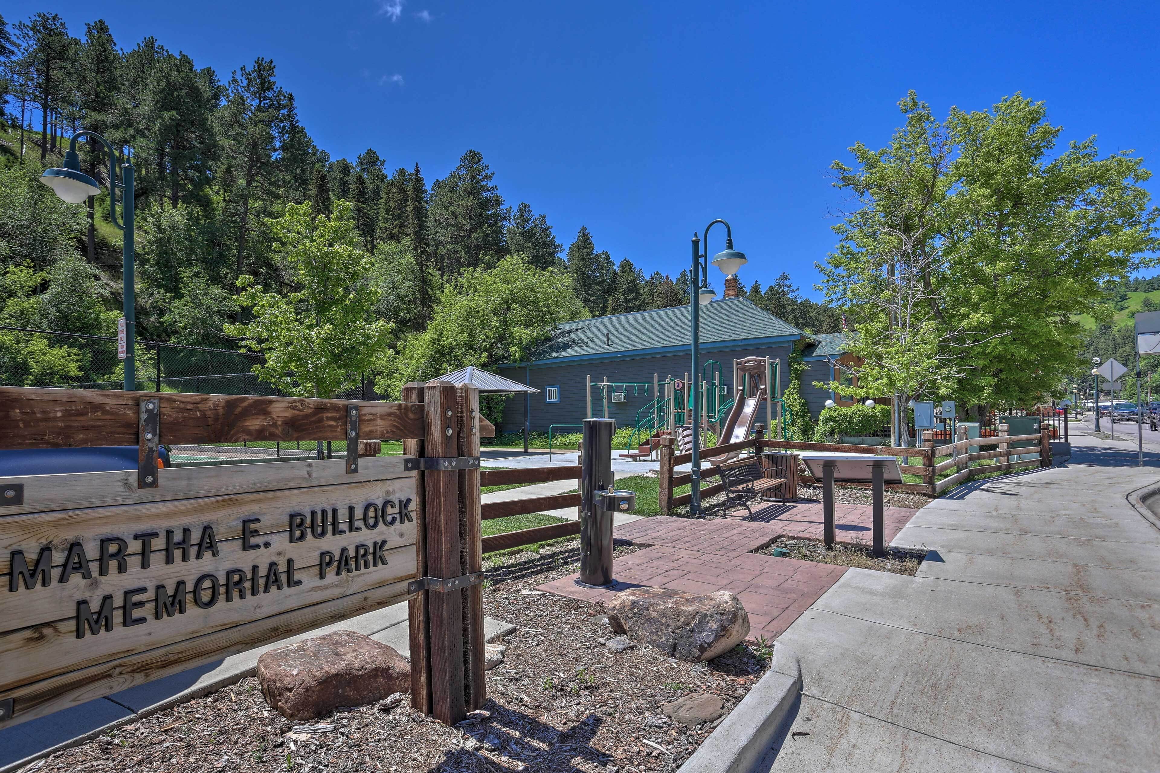 Un panneau en bois portant l’inscription « Parc commémoratif Martha E. Bullock », un chemin piétonnier aménagé et une aire de jeux avec un toboggan et des bancs.