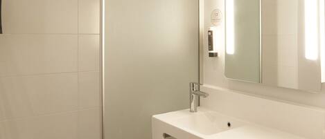 A modern bathroom with a glass shower enclosure, a white sink with a towel, and a mirror above the sink.