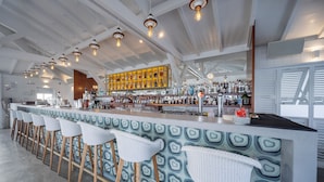 Un bar moderne doté d’un long comptoir, de nombreux tabourets et d’une grande variété de bouteilles et de verres.