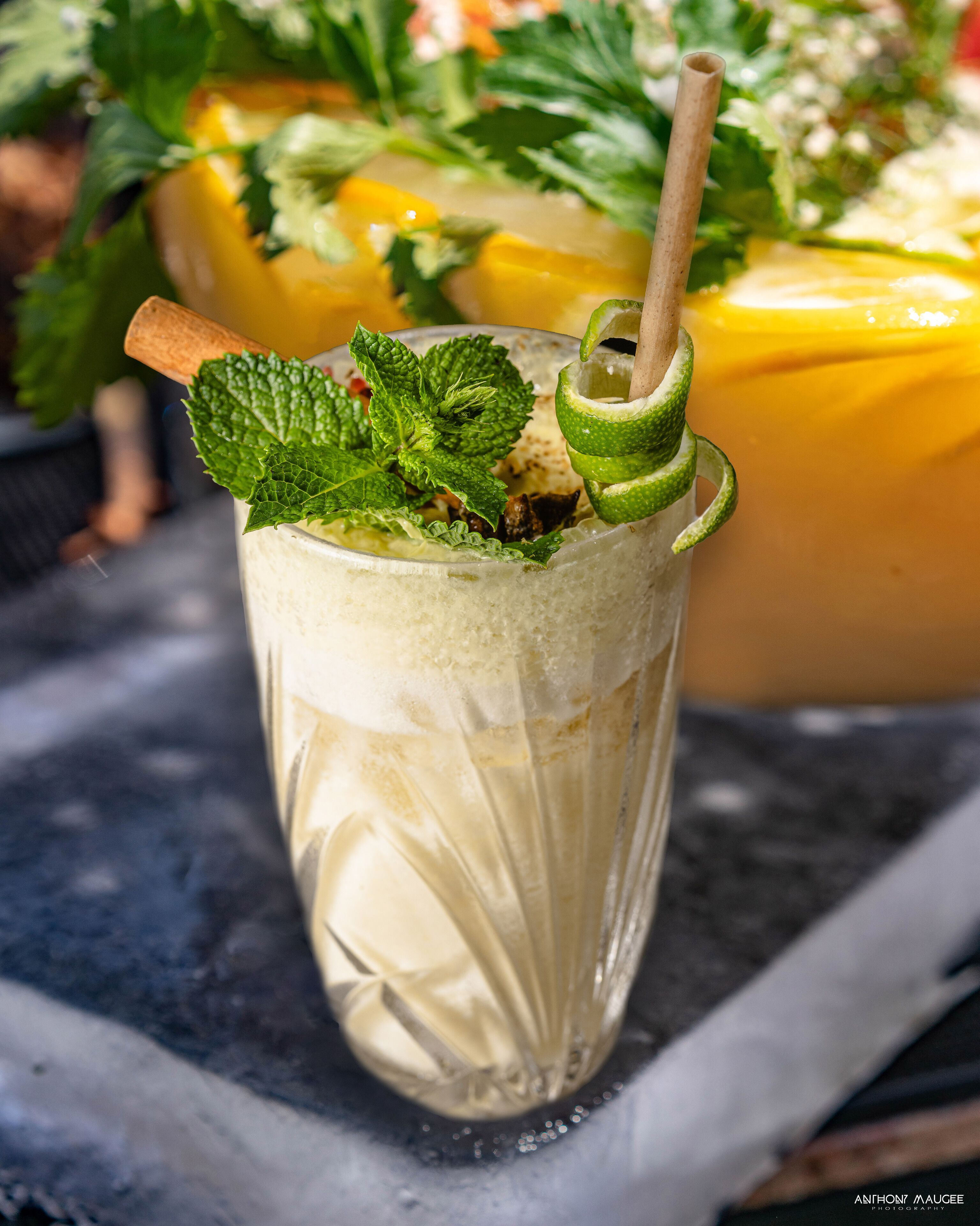A tall glass with a straw, filled with a creamy beverage, garnished with mint and lime.