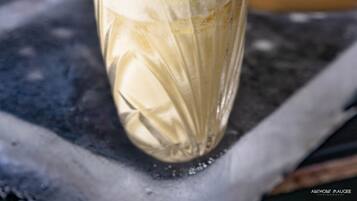 Un grand verre avec une paille, rempli d’une boisson crémeuse, et décoré de feuilles de menthe et d’une tranche de citron vert.