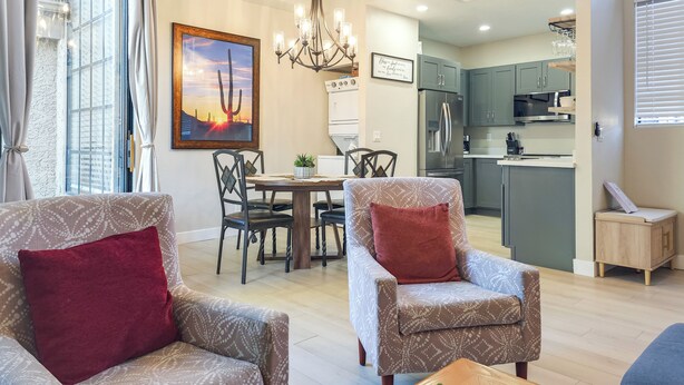 A modern living room with patterned armchairs, a wooden coffee table, and a dining area with a chandelier. - Near Spring Training! Snowbird Mesa Condo w/ Pool (Mesa)