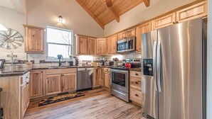 Una cucina con mobili in legno, elettrodomestici in acciaio inossidabile e soffitto in legno.