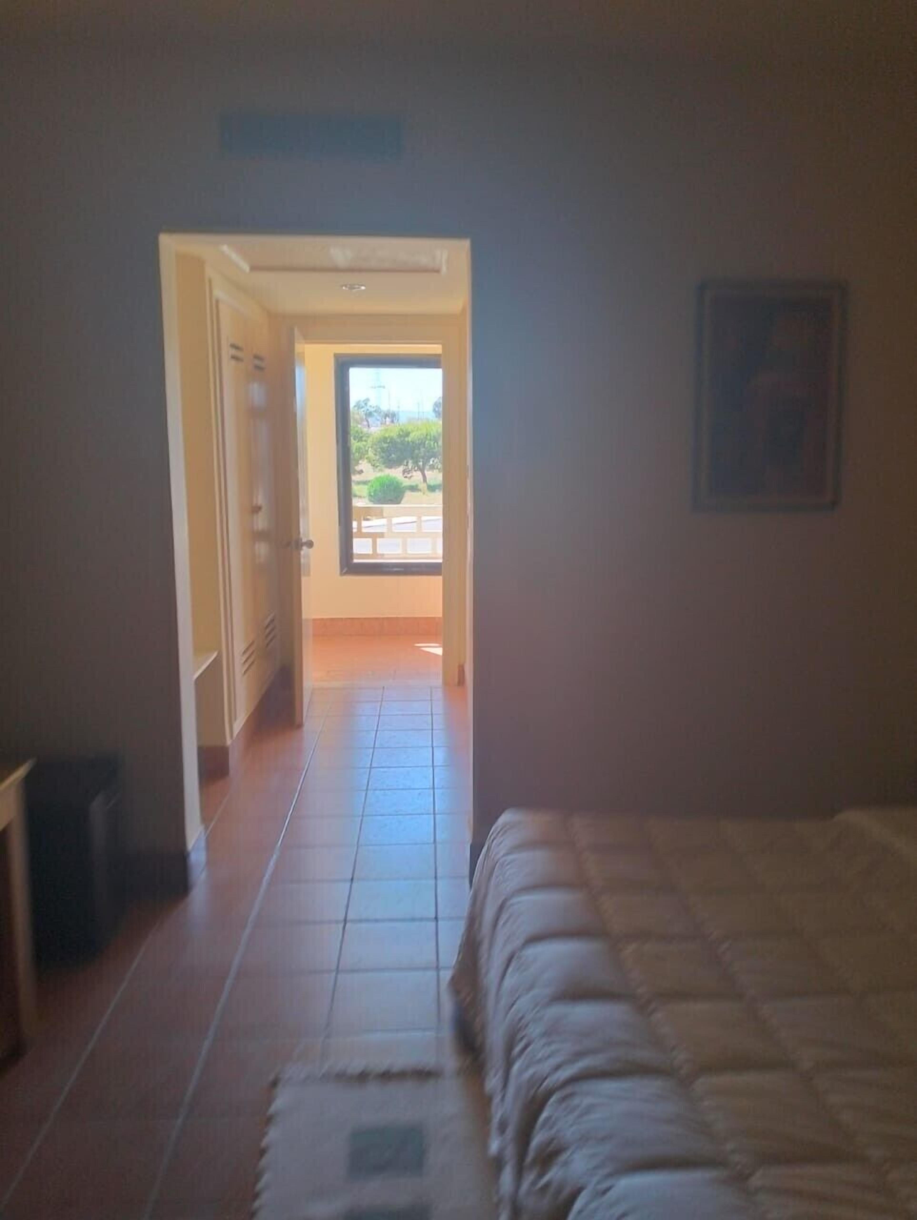 Ein Schlafzimmer mit einem Bett, einer Tür, die auf einen Balkon führt, und einem gefliesten Boden.
