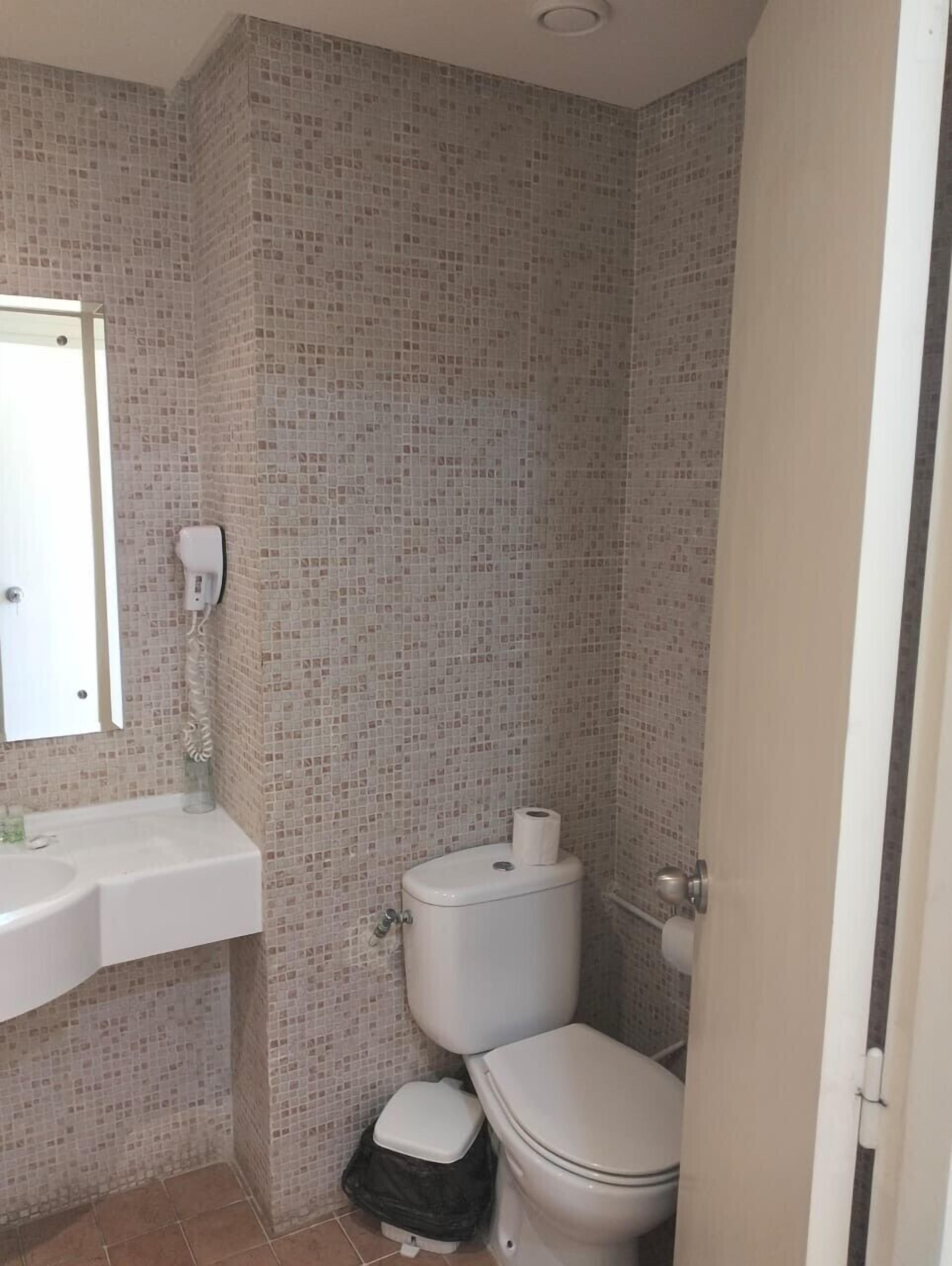 Un baño pequeño con inodoro, lavamanos y espejo.