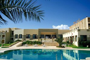 A hotel with a swimming pool, outdoor seating, and a palm tree. - Hotel Sufetula (Subaytilah)
