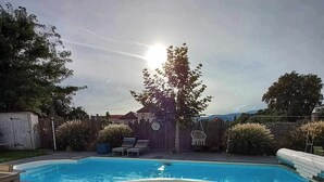 En baghave med swimmingpool, jacuzzi og træhegn.