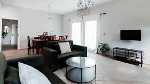 A modern living room with a sectional sofa, a round coffee table, and a TV mounted on the wall. - Evgenias sea view apartments (Parga)