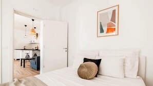 A bedroom with a bed, pillows, a framed picture, and a view into the kitchen. - Evgenias sea view apartments (Parga)