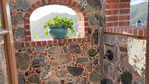 A stone-walled room with a small window and a potted plant. - MandeVilla Cottage at Ixora spectacular views AC in bedroom mid island location. (St.John)