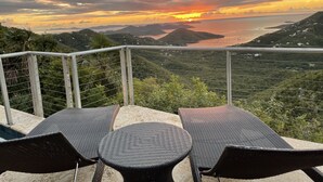 A terrace with wicker furniture overlooking a scenic sunset view. - MandeVilla Cottage at Ixora spectacular views AC in bedroom mid island location. (St.John)